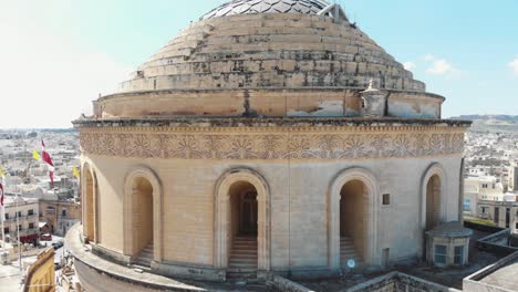 Closeup-aerial-4k-drone-footage-of-the-Mosta-Rotunda-Dome,-a-Roman-Catholic-church,-moving-away-to-reveal-the-surroundings-of-a-city-in-Malta