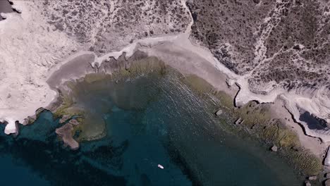 Patagonische-Landschaft-Einer-Wunderschönen-Küste-Mit-Kleinem-Boot,-Das-Auf-Dem-Kristallklaren-Meer-Schwimmt---Luftaufnahme-Von-Oben-Nach-Unten