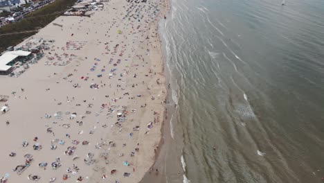 Aerial-footage-tilt-revealing-a-coastline-beach-of-the-city-of-Zandoort,-Netherlands-along-the-North-Sea