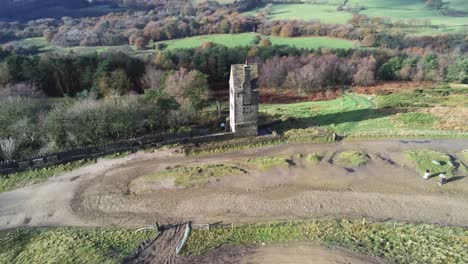 Historic-creepy-fairy-tale-Rivington-pigeon-tower-aerial-wide-right-orbit-overlooking-English-Winter-hill-farming-countryside