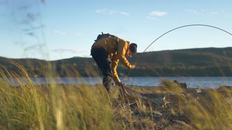 Man-Inserting-tent-poles-through-tent-frame-amidst-Swedish-wilderness---Ground-level-medium-slow-motion-shot