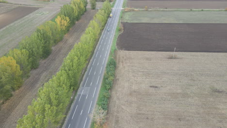 Drone-flies-over-rural-highway-with-light-traffic-to-reveal-miles-of-farmland