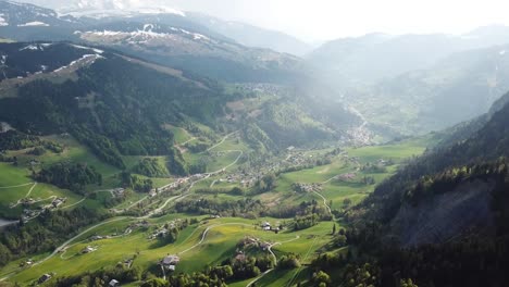 French-Alps-village-in-valley-on-sunny-day,-aerial-pull-away-reveal