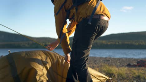 Camper-Laying-down-ground-cloth-to-pitch-a-tent-in-Sweden-wilderness---Medium-close-up-tracking-slow-motion-shot