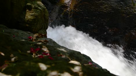 Rapid-water-splashing-in-the-creek,-small-yet-powerful-water-stream-flowing-down-fast-through-rocks