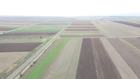 Brown-and-green-fields-flying-over-drone-pan-farm-meadows-on-overcast-day