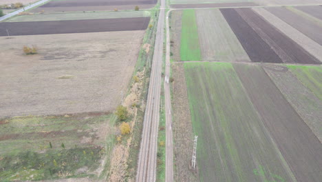 Drohnenantenne-Kippt-Eine-Ländliche-Landstraße-Zwischen-Bauernhof-Und-Wiesen-Hinauf