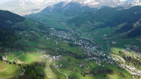 Town-in-French-Alps-valley-during-spring,-snow-on-mountaintops,-aerial-view