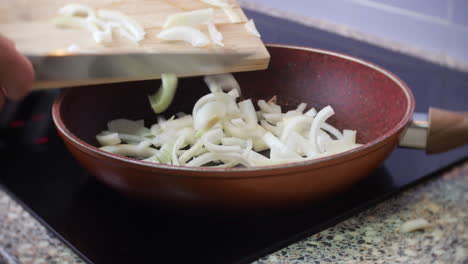 Chopped-onions-are-added-to-a-frying-pan