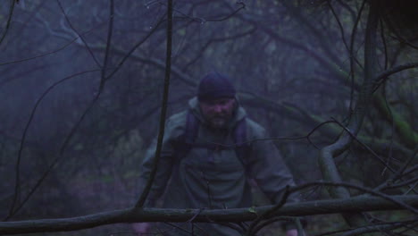 Exhausted-Adult-man-walking-through-foggy-and-rainy-forest-in-wilderness