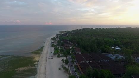 drone-fly-above-Gili-Trawangan-Island,-Lombok,-Indonesia-during-stunning-sunset,-white-sand-beach-pristine-ocean-water-and-green-jungle-vegetation,-cinematic-footage-of-tropical-travel-destination