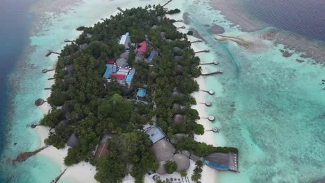 Tropical-island-in-Maldives-with-piers-and-docks-close-to-white-sandy-beach,-resorts-and-restaurants-into-palm-trees-forest