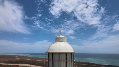 Aerial---Vlamingh-Head-Lighthouse-in-Pacific-Ocean,-Western-Australia,-close-to-town-and-blue-sky-and-clouds,-orbit-circle-shot