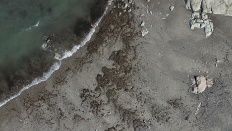 Aerial-Drone-bird-eye-view-of-rocky-beach-and-clear-surf