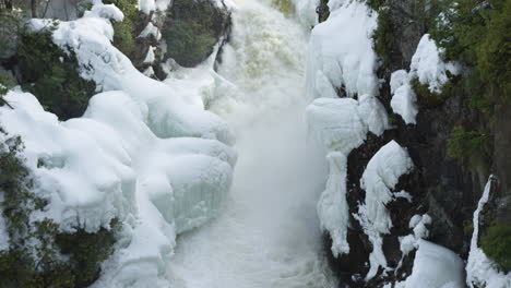 Incredible-slow-motion-shot-of-a-river-flowing-into-a-frozen-waterfall-in-a-forest-landscape