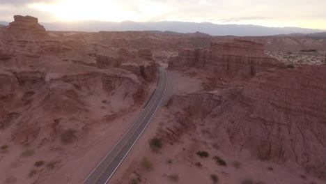 Aerial---road-in-a-canyon-at-dawn-in-Cafayate,-Argentina,-wide-shot-forward
