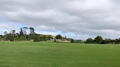 Grounds-maintenance-vehicle-moving-along-the-green-field-on-a-windy-day-in-Auckland-New-Zealand---timelapse