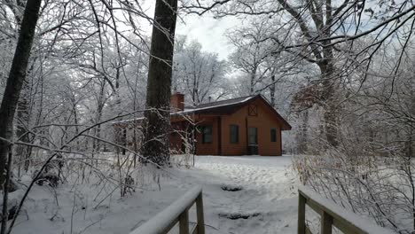 Wooden-Cabin-in-Winter-Wonderland-Reveal-Bridge,-Pull-back