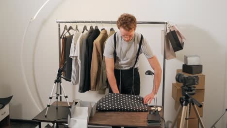 Pleasant-young-man-packs-clothes-to-send-a-parcel