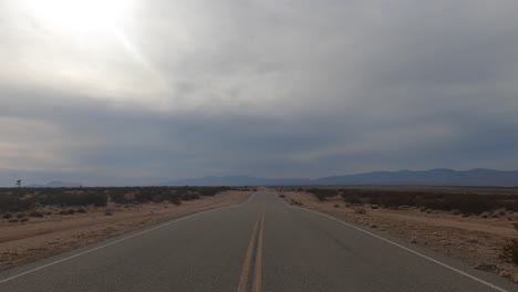 From-the-point-of-view-of-a-person-driving-a-car-through-the-Mojave-Desert-on-a-stormy-day