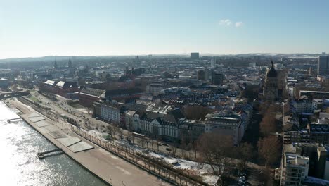 Drone-flight-over-a-snowy-Mainz-the-City-of-Biontech-on-a-sunny-Winter-day-showing-flood-of-the-Rhine-river-and-blue-sky