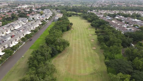 Aerial-view-of-Golf-course-with-trees,-residential,-pond-and-highway