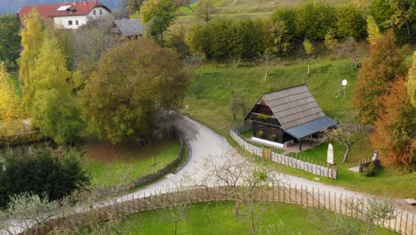 Aerial-approaching-small-rustic-house,-charming-wood-fence