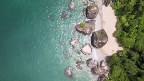 Gliding-amidst-the-glistening-turquoise-sea,-small-beach-of-giant-stones,-and-Atlantic-rainforest-in-Angra-dos-Reis,-Rio-de-Janeiro,-Brazil