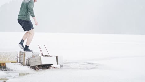 Man-Walking-On-Broken-Jetty-Towards-Frosted-Lake-In-Trondheim,-Norway-During-Snowstorm