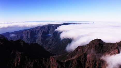 Aerial-view-overlooking-mountain-peaks-and-clouds,-in-Madeira---pan,-drone-shot
