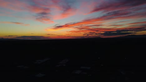 Drone-flying-over-neighborhood-into-beautiful-golden-hour-sunset-with-brightly-colored-clouds,-appearing-as-if-it's-not-moving-anywhere-at-all