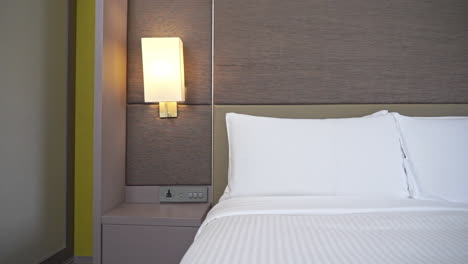 Langsamer-Schwenk-Direkt-Auf-Klassisches-Hotel-Schlecht-Geschminkt-Mit-Hoher-Matratze-Und-Angeschaltetem-Licht-An-Lampe