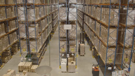 High-angle-view-of-forklift-with-boxes-driving-through-industrial-warehouse
