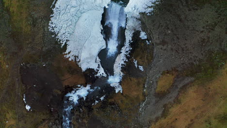 Svodufoss-Waterfall-Cascading-Down-On-Basalt-Column-Cliff-Covered-In-Ice-At-Winter-In-Iceland