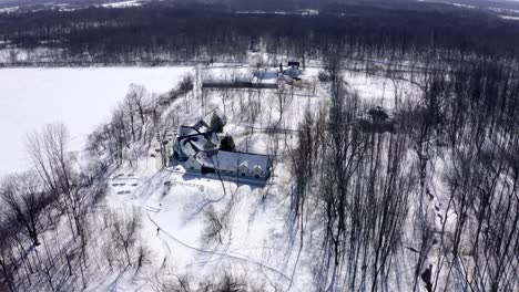 Aerial-shot-turning-around-a-large-chalet-on-a-beautiful-sunny-winter-day