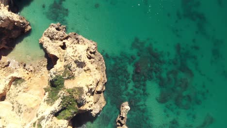 Bird's-eye-view-of-cliffs-and-crystal-clear-ocean-on-a-calm-day,-Lagos,-Algarve,-Portugal