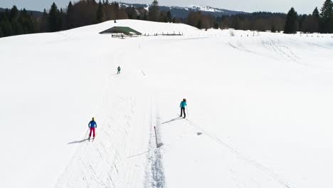 Aerial-view-showing-female-group-cross-country-skiing-in-french-mountains-during-sunny-day-in-winter