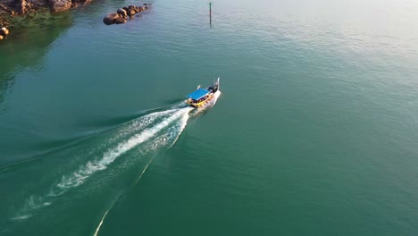 Aerial-birds-eye-view-capturing-a-traditional-fishing-boat-sailing-out-to-the-ocean-to-catch-fish-at-Langkawi-island,-Malaysia,-Southeast-Asia