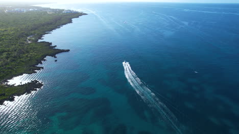 Boat-moving-through-a-caribbean-coast-with-stunning-water-depth-and-color,-epic-aerial-view