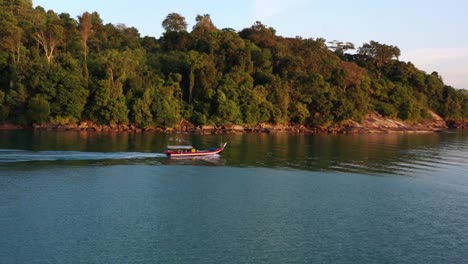 Aerial-tracking-shot-capturing-a-traditional-gondola-fishing-boat,-sailing-out-to-the-ocean-to-catch-fish-at-beautiful-sunset-golden-hour,-Langkawi-island,-Malaysia,-Southeast-Asia