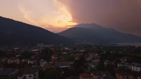 Drone-shot-of-sunset-clouds-with-mountains-near-a-lake