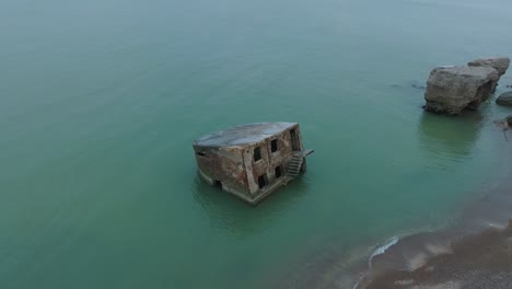 Aerial-birdseye-view-of-abandoned-seaside-fortification-building-at-Karosta-Northern-Forts-on-the-beach-of-Baltic-sea-,-overcast-day,-wide-drone-shot-moving-forward,-camera-tilt-down