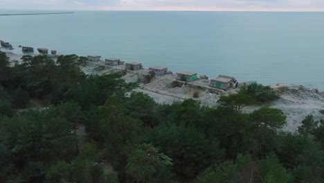 Establishing-aerial-view-of-abandoned-seaside-fortification-buildings-at-Karosta-Northern-Forts-on-the-beach-of-Baltic-sea-,-overcast-day,-wide-drone-shot-moving-forward,-tilt-down