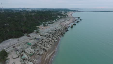 Establishing-aerial-view-of-abandoned-seaside-fortification-buildings-at-Karosta-Northern-Forts-on-the-beach-of-Baltic-sea-,-overcast-day,-wide-drone-shot-moving-forward-high
