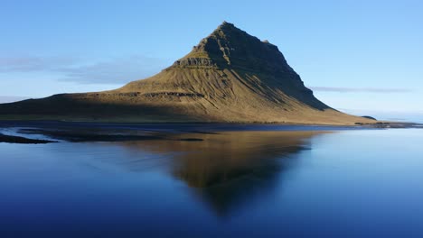 Kirkjufell-mountain-in-Iceland-reflected-on-still-water,-low-wide-pan