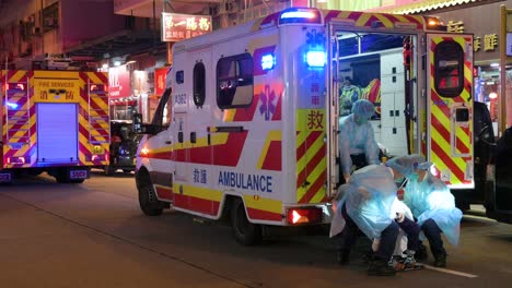 Ein-älterer-Patient-Wird-Auf-Einer-Trage-Zu-Einem-Krankenwagen-Getragen,-Während-Ein-Ersthelferteam-Der-Notfalleinheit,-Darunter-Feuerwehrleute-Und-Ein-Medizinisches-Team,-Auf-Einen-Notruf-In-Hongkong-Reagiert