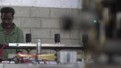 View-Of-Factory-Machinery-Pressing-Down-At-Plastics-Factory-In-Karachi-With-Male-Worker-In-background