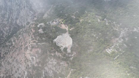 Aerial-Descending-Through-Clouds-To-Reveal-Thermessos-Amphitheatre-On-Hillside