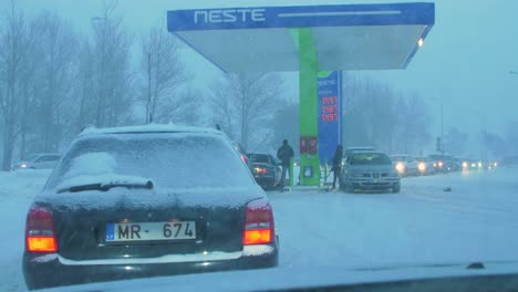 Concurrida-Gasolinera-Neste-Con-Colas-De-Personas-Que-Rellenan-Sus-Coches-Por-Miedo-A-La-Escasez-De-Combustible,-Aumento-De-Los-Precios,-Exageración-En-Las-Gasolineras,-Día-De-Invierno-Nublado-Con-Fuerte-Tormenta-De-Nieve,-Amplio-Tiro-De-Mano