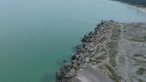 Aerial-birdseye-view-of-abandoned-seaside-fortification-buildings-at-Karosta-Northern-Forts-on-the-beach-of-Baltic-sea-,-overcast-day,-wide-drone-shot-moving-forward,-camera-tilt-down